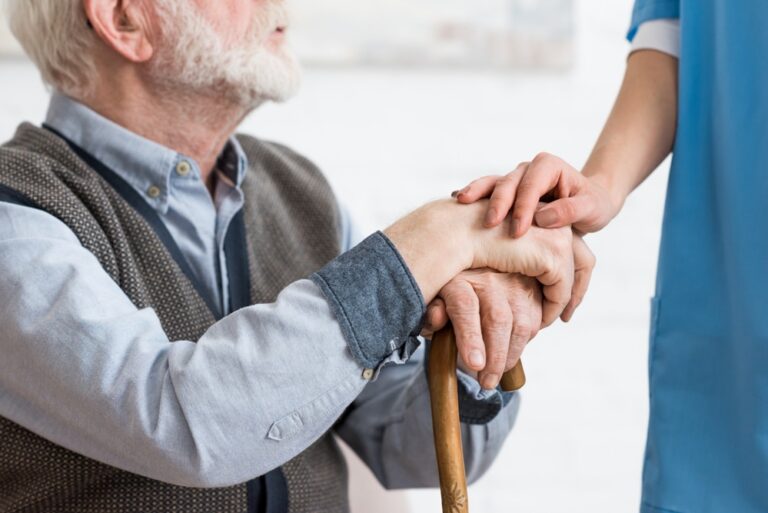 Close-up of senior man with hands on cane