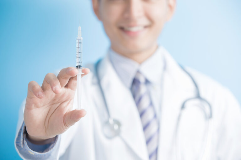 Smiling doctor holding up syringe