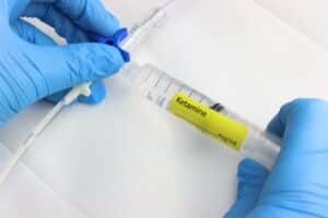 Professional wearing gloves injecting ketamine in a intravenous set